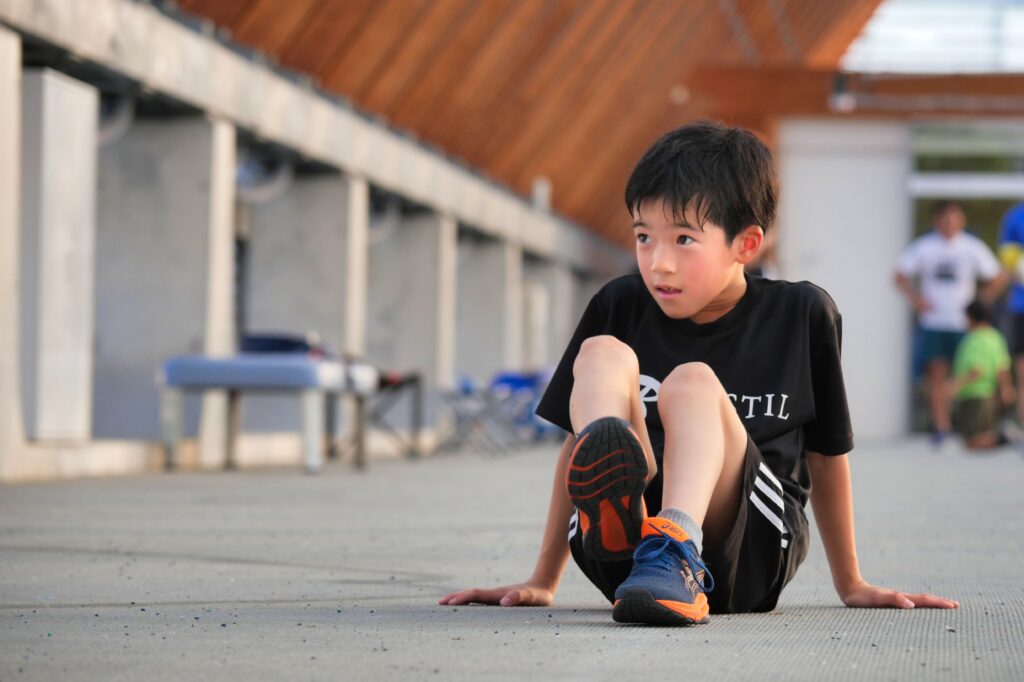 走る前のストレッチをする小学生